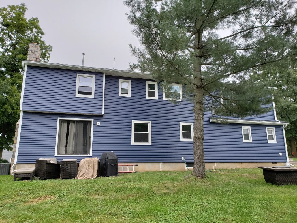 Back of colonial style house with deep dark blue color vinyl traditional clapboard siding in Whippany NJ Morris County white window trim and white corners