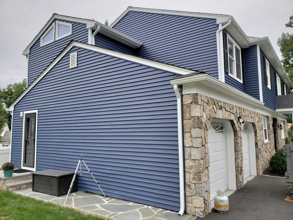 left side of colonial style house with deep dark blue color vinyl traditional clapboard siding in Whippany NJ Morris County white window trim and white corners