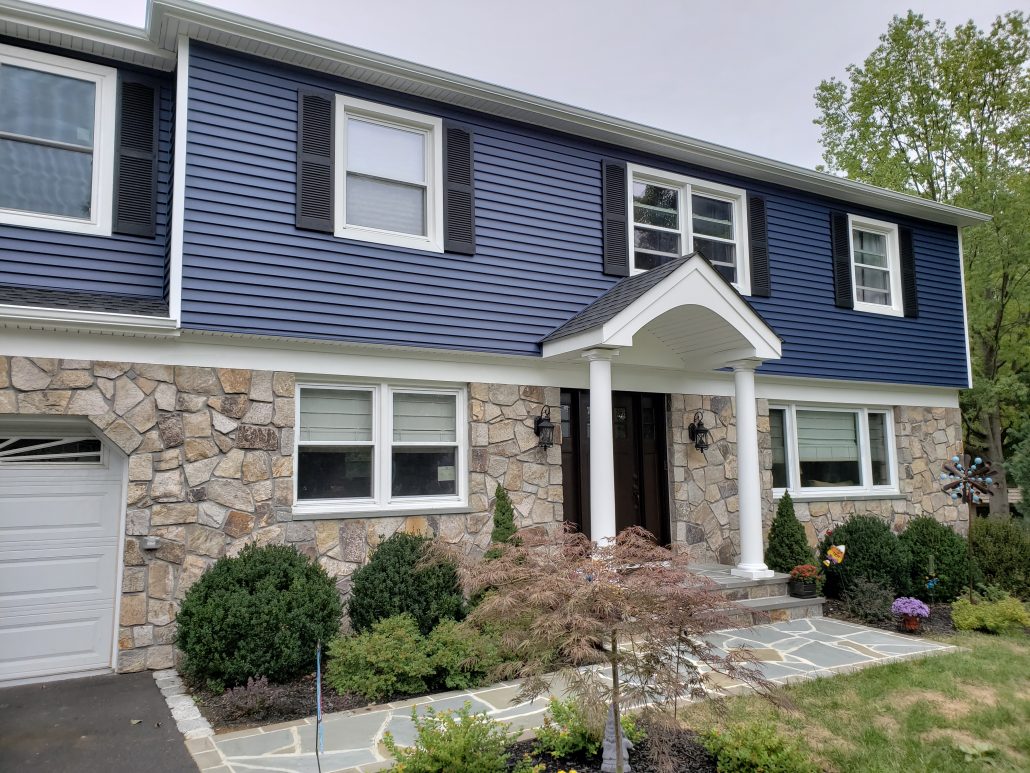 Colonial style house with deep dark blue color vinyl traditional clapboard siding in Whippany NJ Morris County white window trim and white corners 2