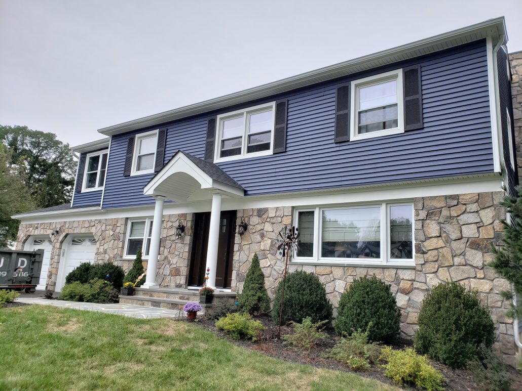 Colonial style house with deep dark blue color vinyl traditional clapboard siding in Whippany NJ Morris County white window trim and white corners